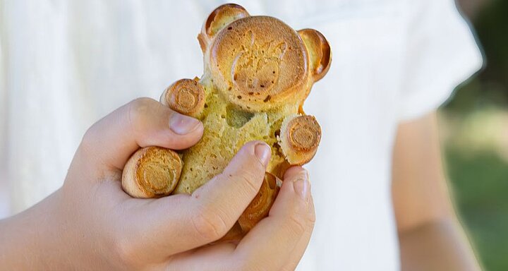 Ruka drží pečivo ve tvaru medvěda.