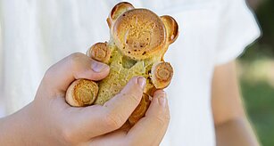 Ruka drží pečivo ve tvaru medvěda.