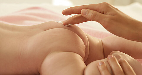 Ruka aplikuje látku na pokožku dieťaťa.