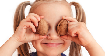 Dievča s dvoma orechmi, ktoré si drží na očiach.