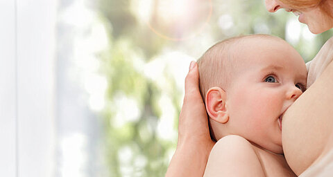 Detailný záber na tvár dieťaťa s rozmazaným pozadím, ktoré je držané za ruku.