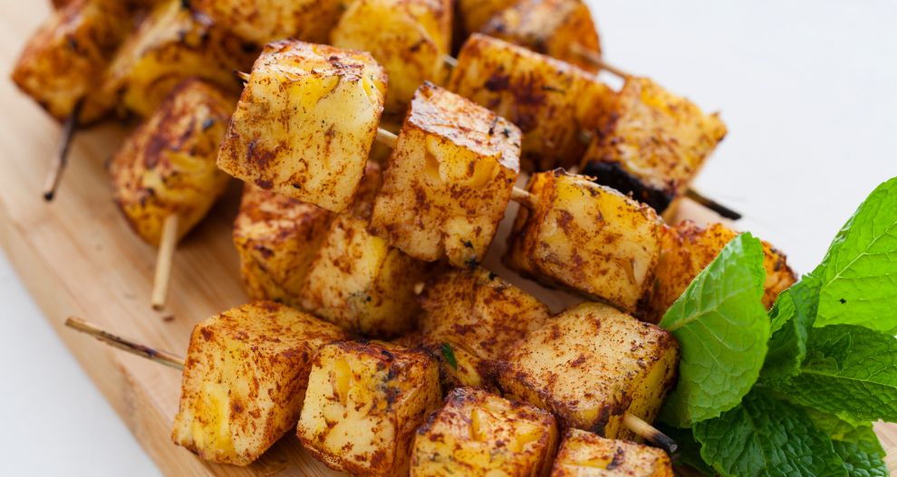 Grilované kousky ananasu na špejli a ozdobené lístky čerstvé máty.