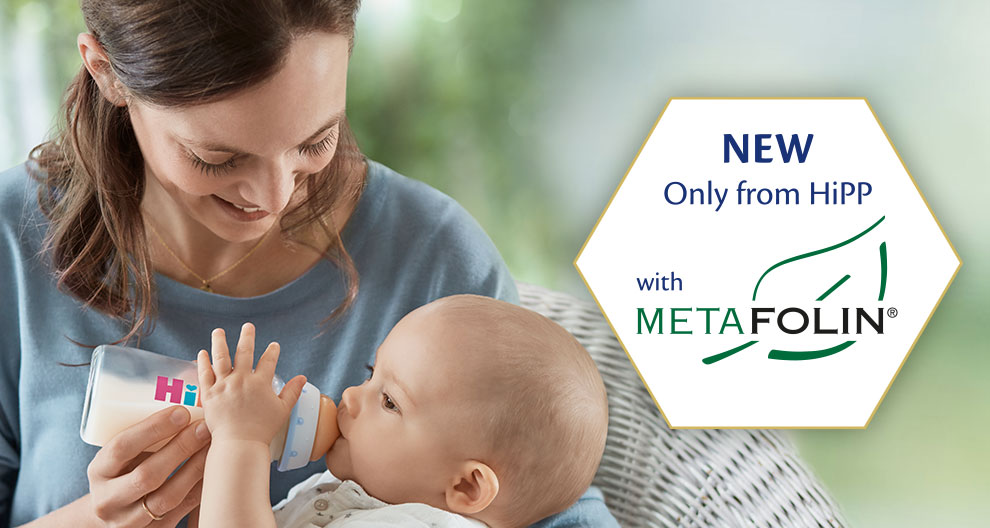 A woman feeds a baby with a bottle, while a hexagonal advertisement highlights a new product feature from HiPP with MetaFolin®.