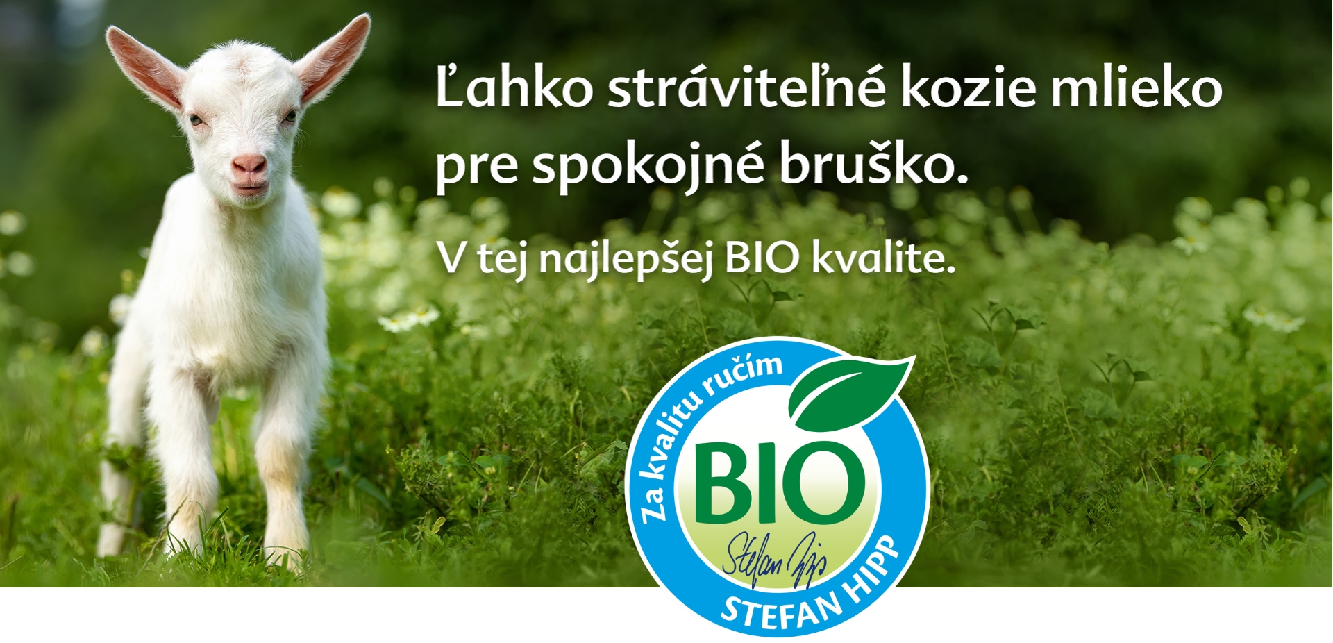 Biela koza stojí na zelenom poli s modrým a bielym logom bio v pravom dolnom rohu.