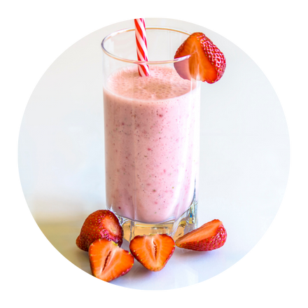Pohár ružovkastého smoothie so slamkou a nakrájanými jahodami.