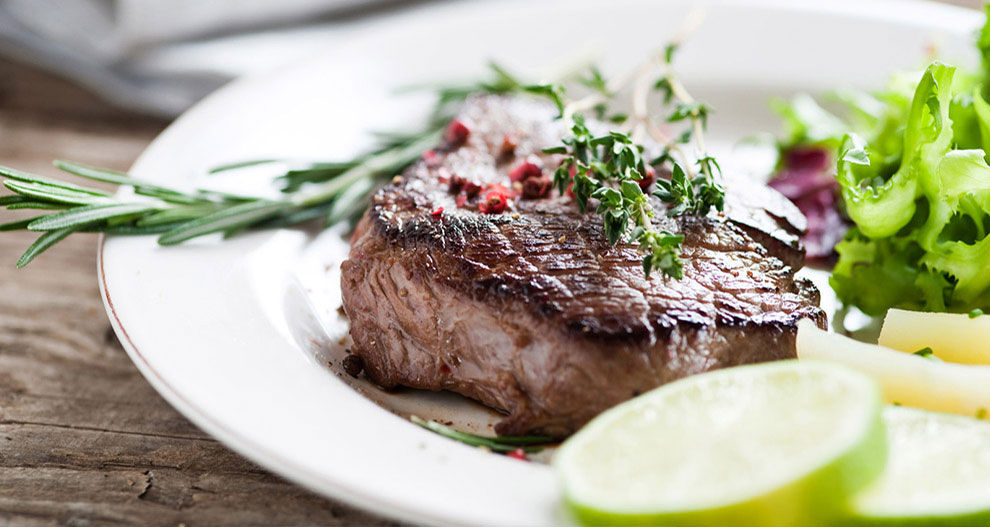 Steak s rozmarínovou a tymiánovou oblohou, podávaný spolu so zeleným šalátom a plátkami limetky.