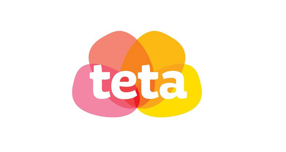 Logo so slovom "teta" napísaným malými písmenami, ktoré je umiestnené v strede symetrického dizajnu tvoreného prekrývajúcimi sa kruhmi v odtieňoch ružovej, oranžovej a žltej farby.