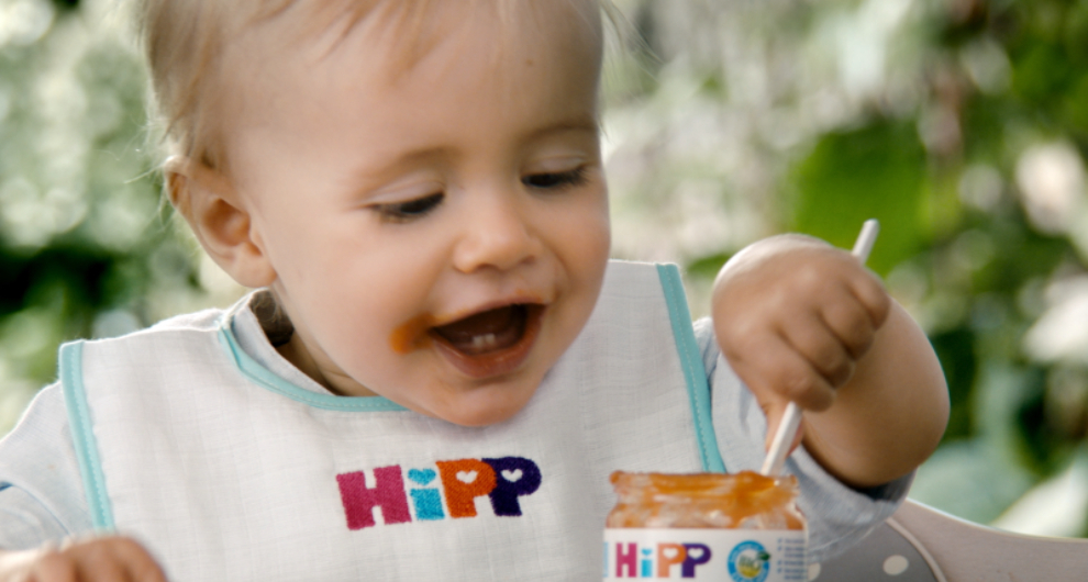 Dieťa s podbradníkom s nápisom "HIpp" papá z pohára.